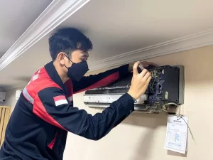 Foto teknisi Refcon sedang men-service AC yang mengalami kerusakan.